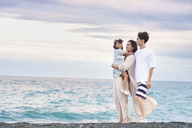 家族が海辺で寄り添って歩いている様子